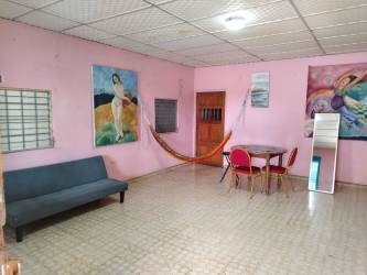 Living space with sofa, hammock, dining table and pink walls in affordable student rental Veraguas Panama