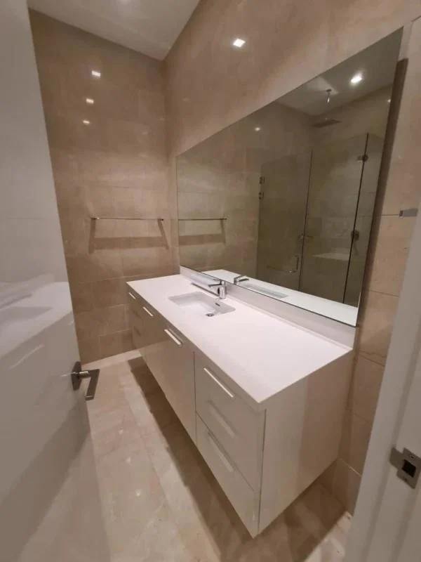 Contemporary bathroom with beige tiles, glass shower in luxury Panama City apartment