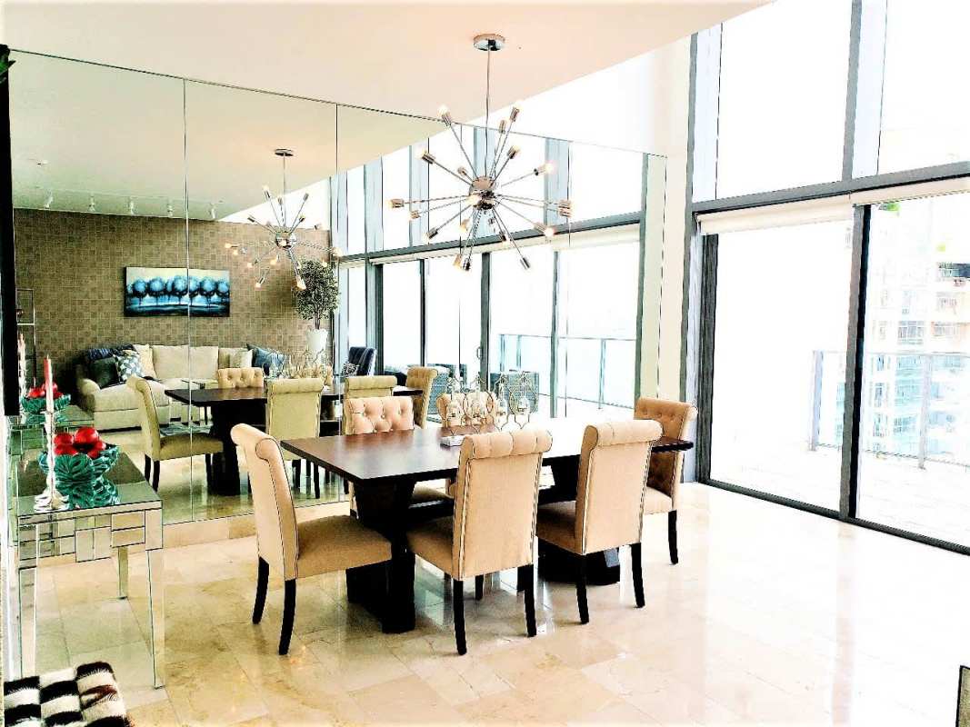 Dining area with large windows, mirrored wall, modern chandelier in Grand Tower Punta Pacifica