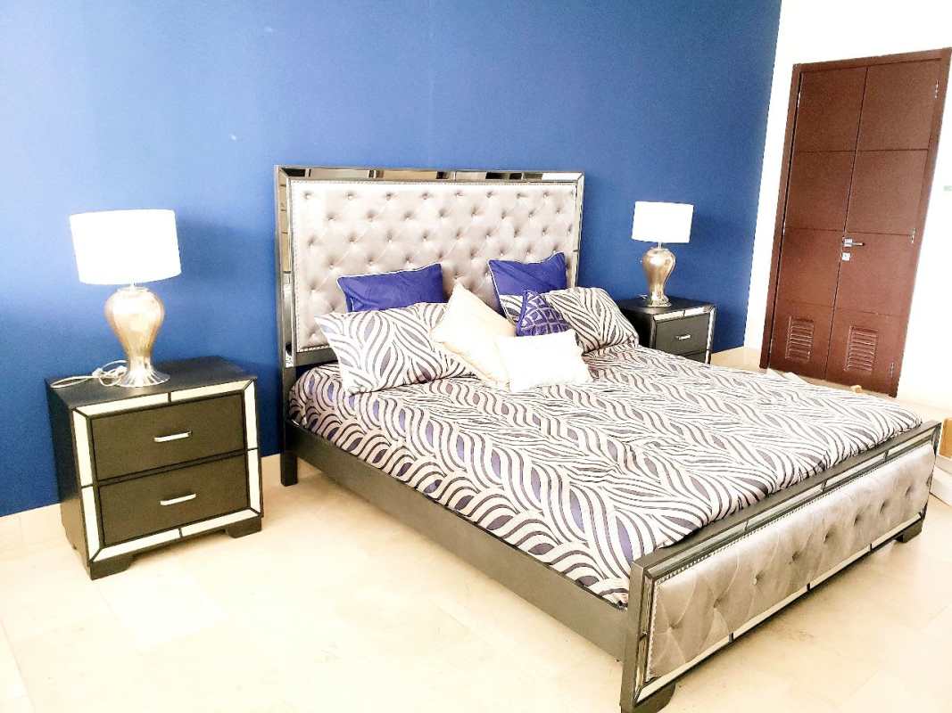 Modern bedroom with blue accent wall, tufted bed, metallic lamps in Grand Tower Punta Pacifica Panama
