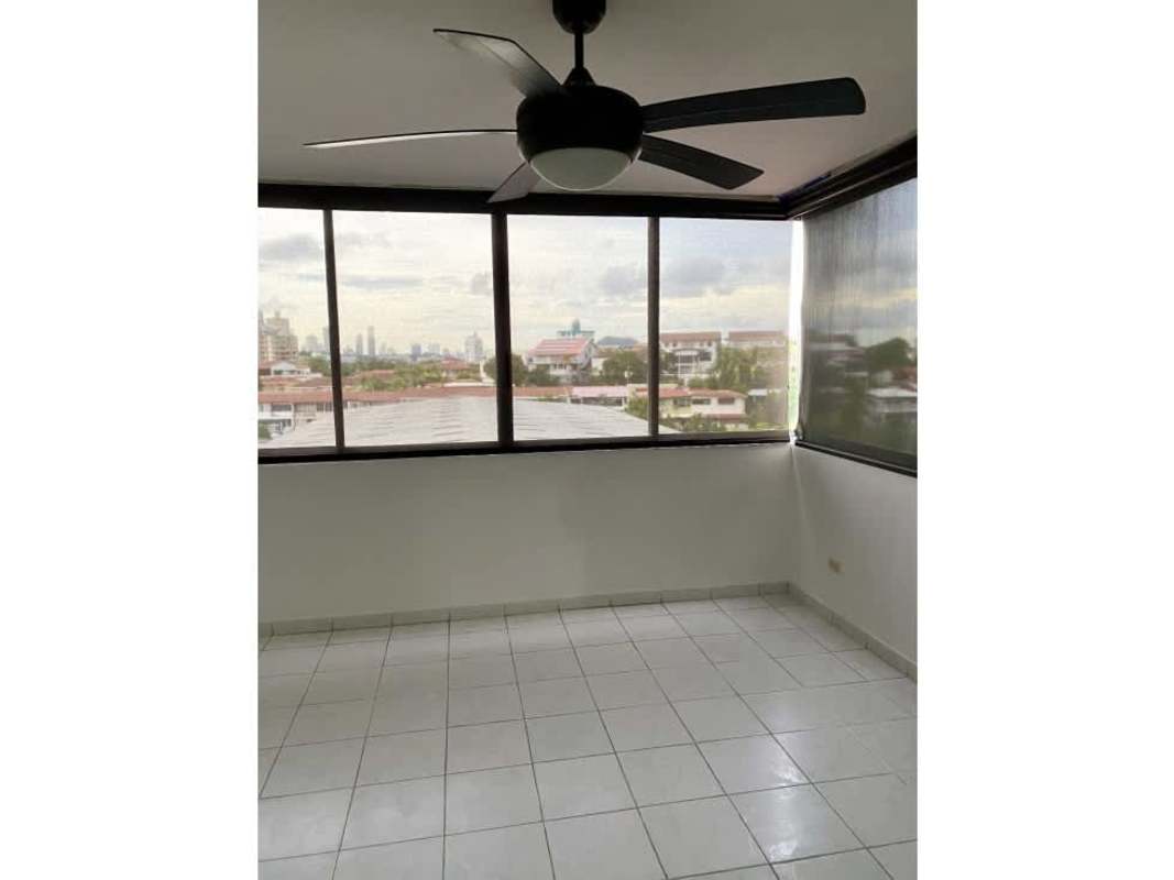 Sunroom area with large windows overlooking city, white tiled floors, ceiling fan