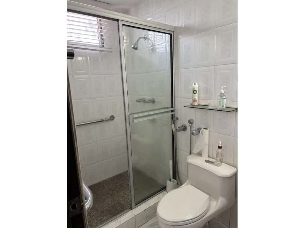 Bedroom with large corner windows, ceiling fan, wood feature wall