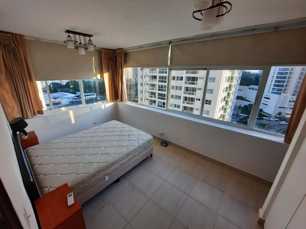 Spacious living-dining area with large window, beige sofa, dining table, chandeliers, city view in Edison Park Panama