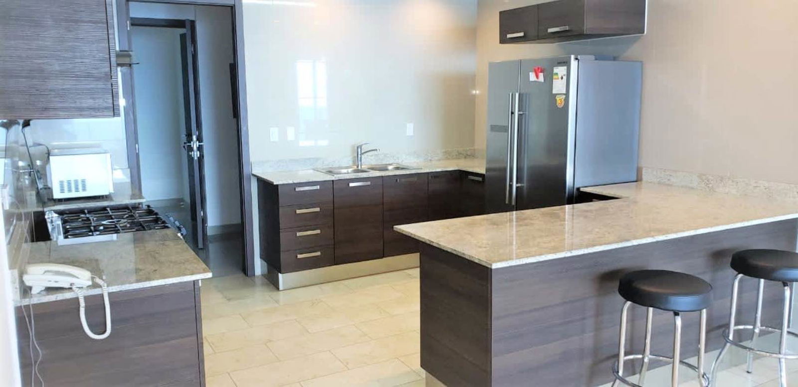 Modern kitchen featuring granite countertops, stainless appliances, bar seating in PH Grand Tower Punta Pacifica Panama