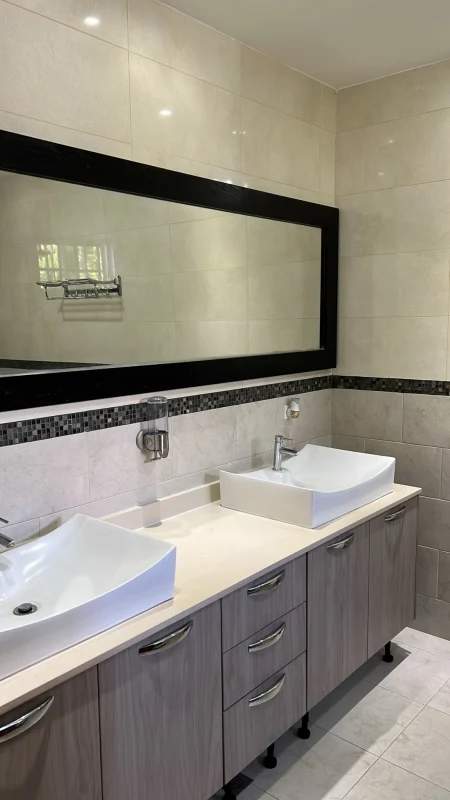 Bathroom with double vessel sinks, black framed mirror and mosaic tile accents in Llanos de Curundu house