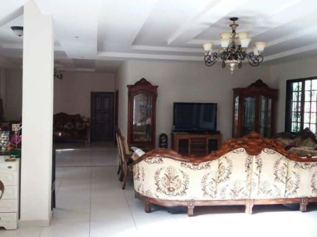 Traditional dining room with large wooden table, marble wall accents, chandelier in Curundu Panama home
