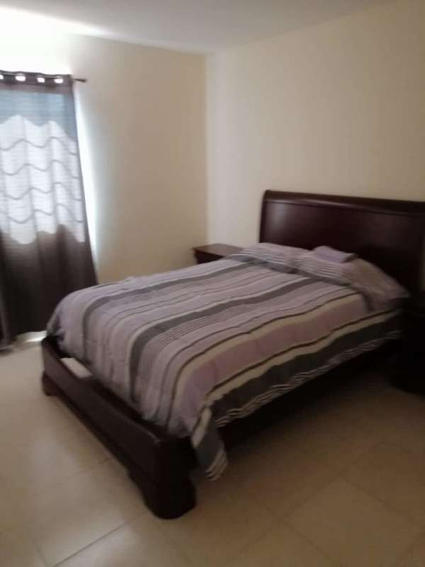 Bedroom with striped bedding, curtains, AC unit in furnished 4BR house near Brisas del Golf Panama