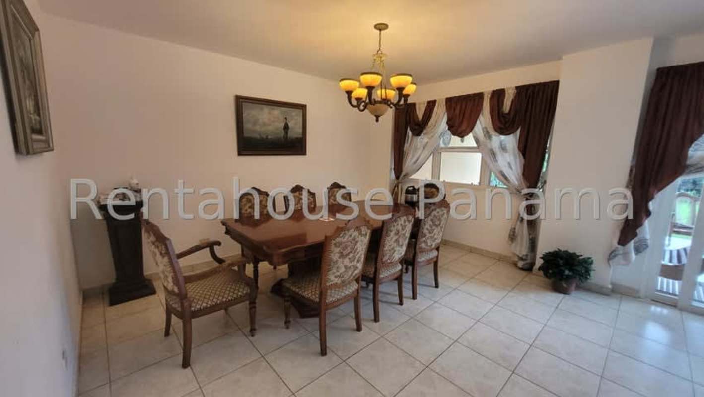 Covered terrace with dining furniture and garden view at Villas del Golf house for rent in Panama City