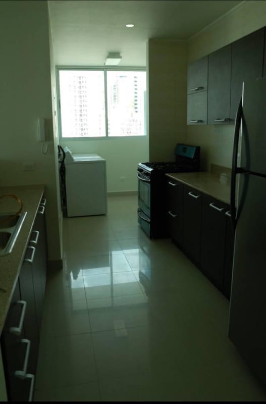 Contemporary kitchen with granite countertops, dark wood cabinets, stainless steel appliances, and laundry in PH Pacific Sea Punta Pacifica Panama