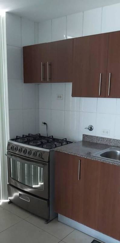 Apartment kitchen with granite countertops, wooden cabinets, gas stove and refrigerator in PH Green Point Carrasquilla Panama City