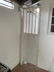 Utility laundry space with metal door and white pipes in affordable house La Chorrera Panama