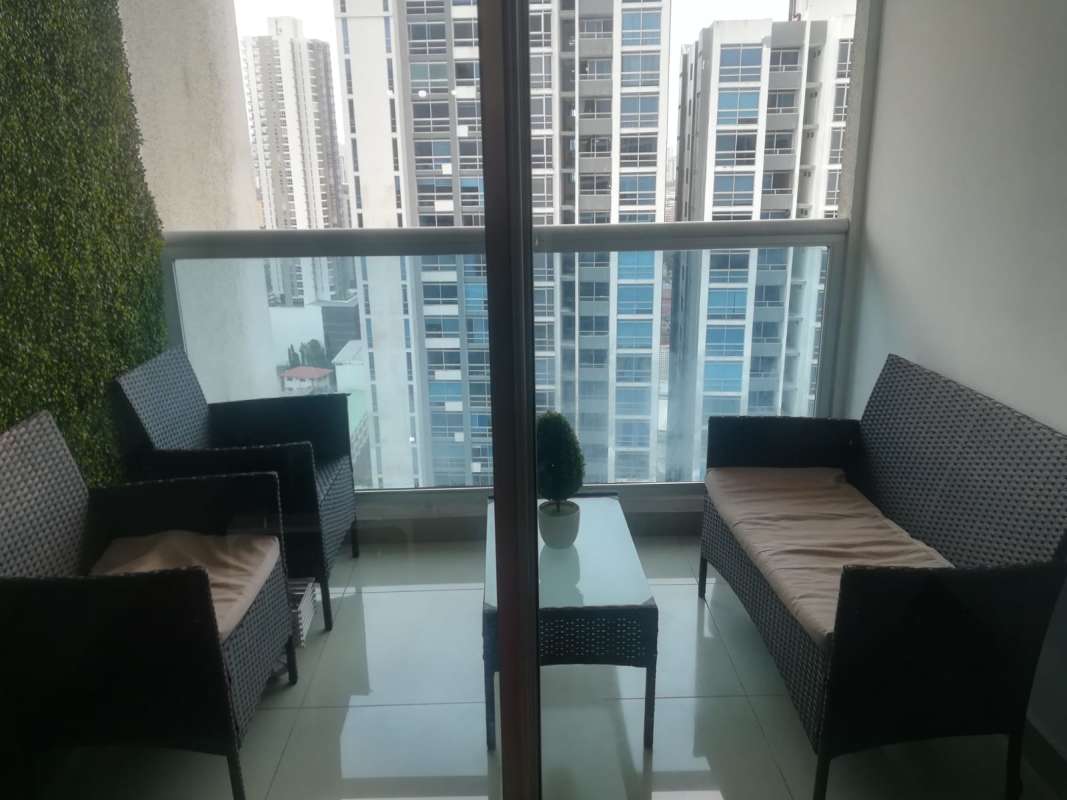 Modern living room with gray sofa and large window city view at PH Coral Tower