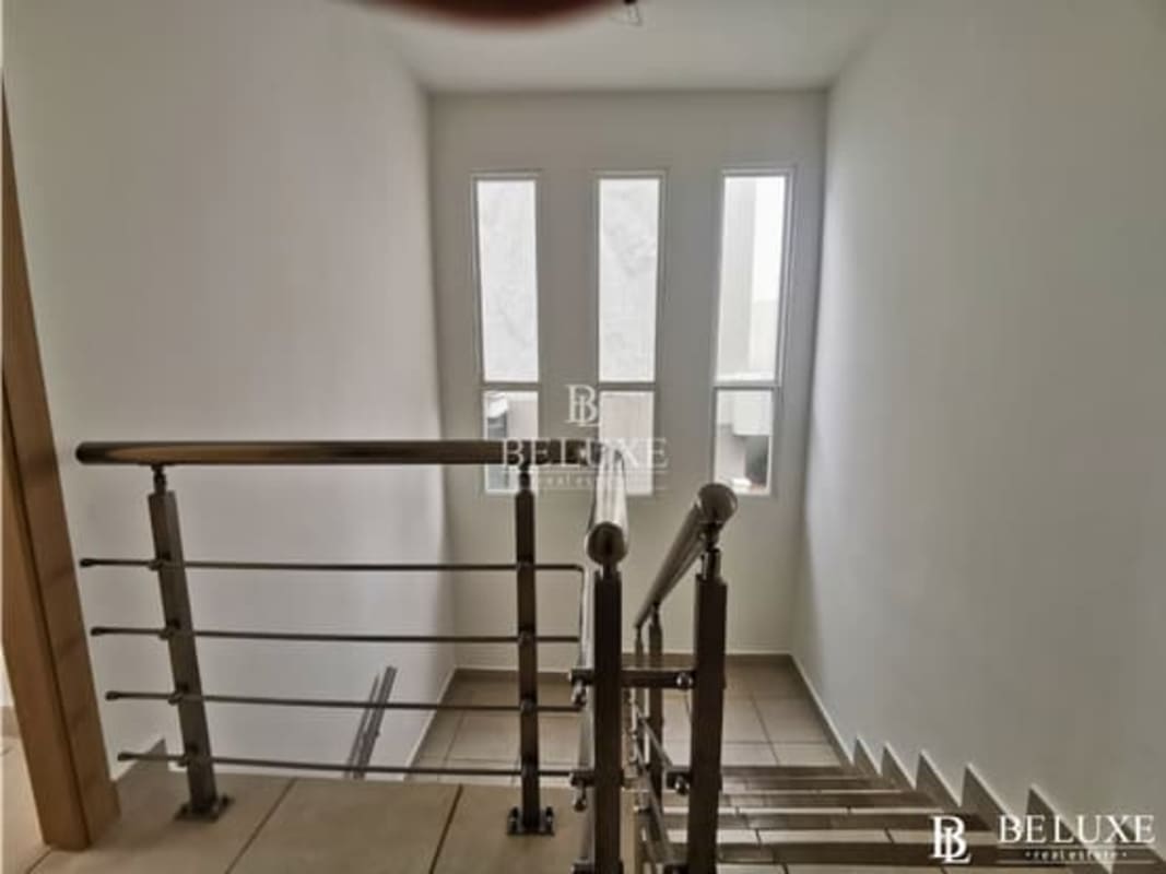 Staircase landing with stainless railing and windows in PH Victoria house Brisas del Golf