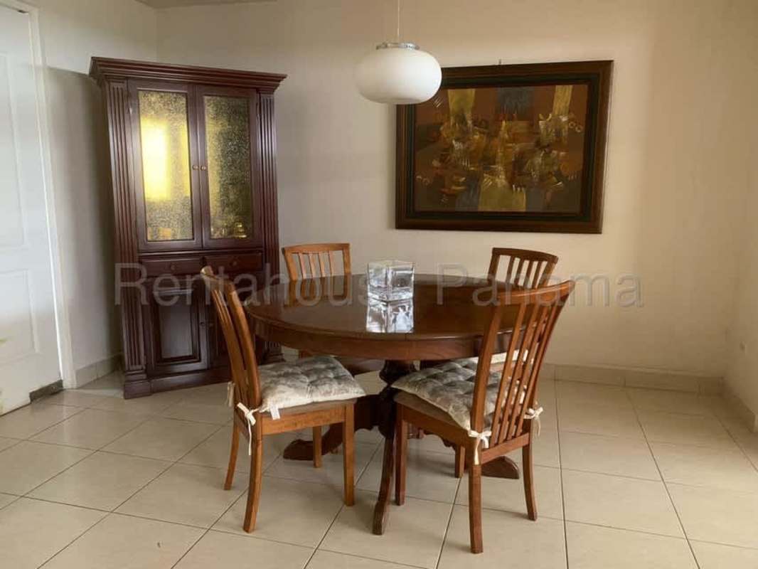 Dining room with wooden round table, chairs, pendant light and cupboards in Condado del Rey Panama