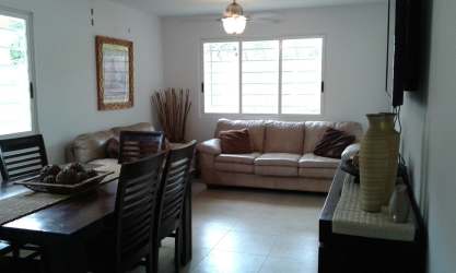 Spacious living and dining room with beige sofas, dining table, large windows at C Paradise Village Coronado Panama