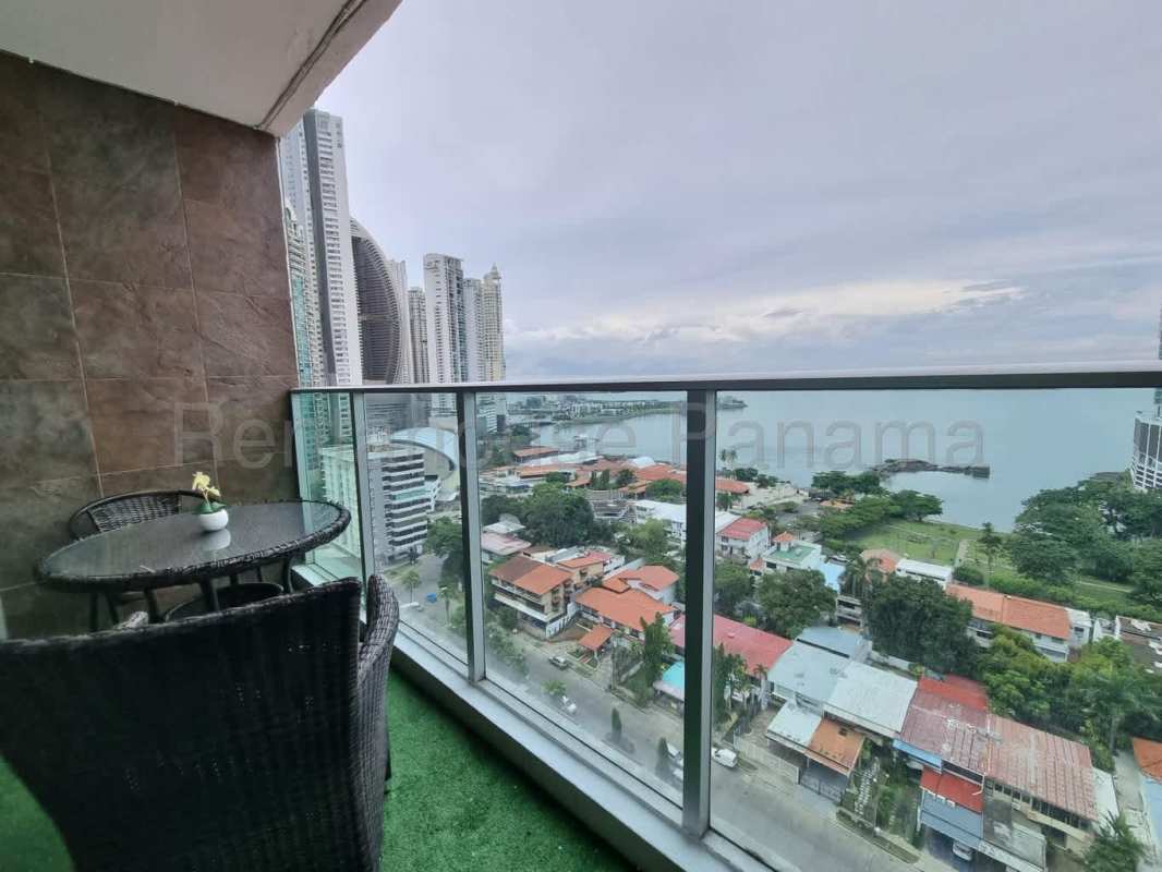 Panoramic balcony with wicker chairs, table, artificial turf floor overlooking oceanfront Panama City