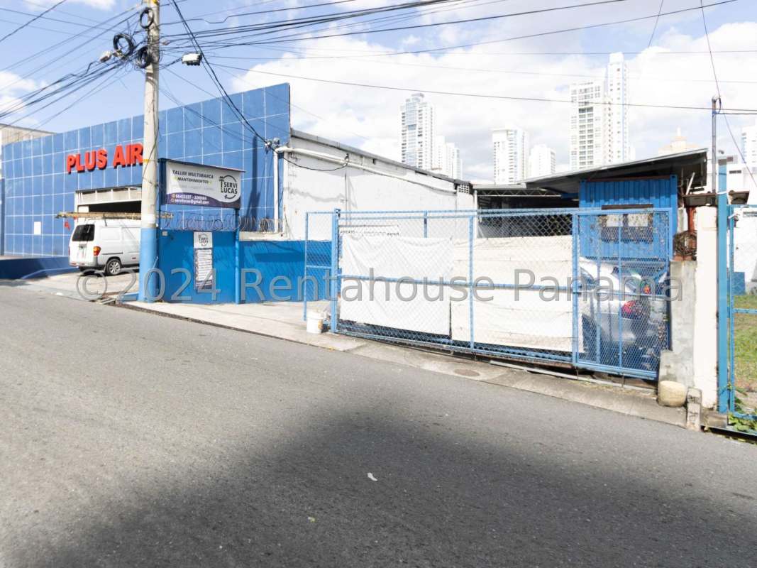Street side facade with blue automotive shop and fenced parking area in Panama City