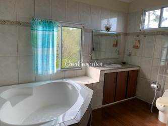 Bathroom with large window corner bathtub tiled walls natural light in Boquete Panama