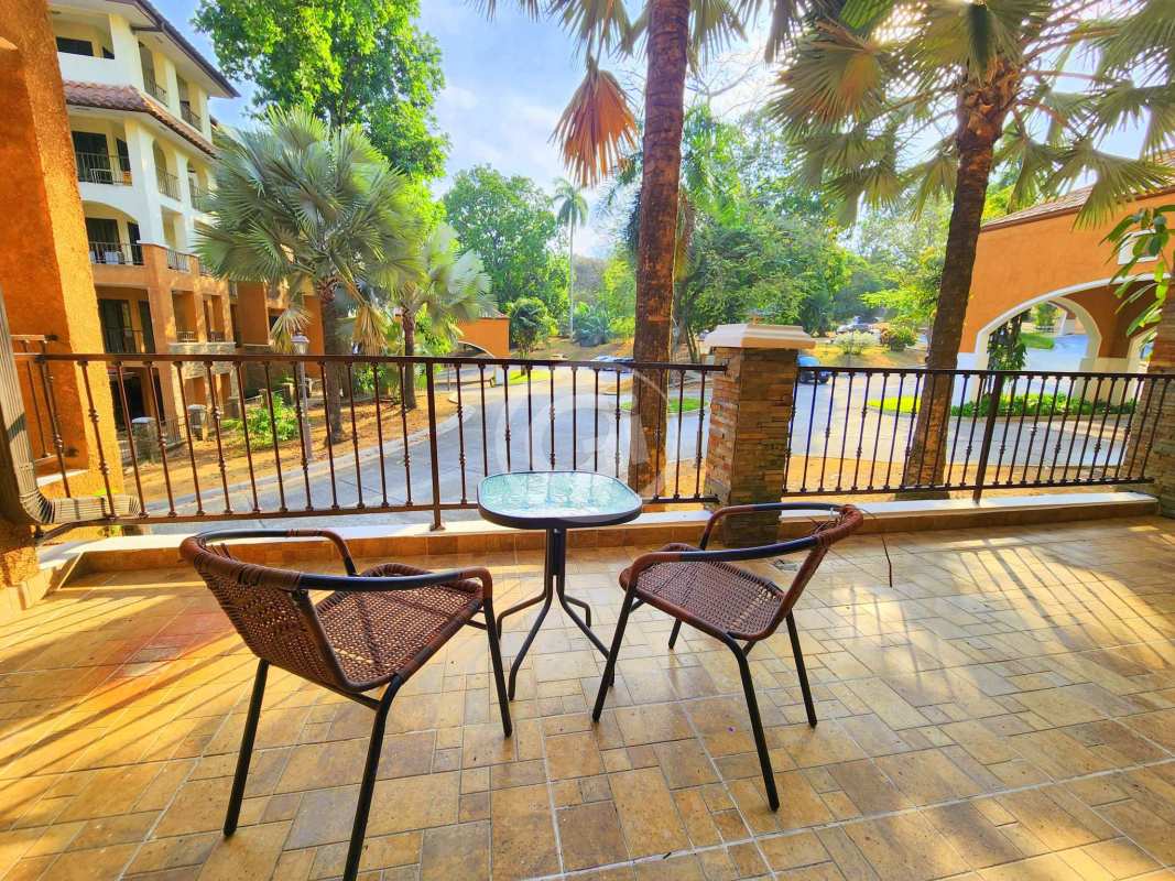 Large tiled balcony with iron railings surrounded by lush gardens in Embassy Club Clayton