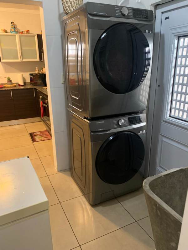 Laundry room equipped with stacked washer dryer and utility sink in PH Olymphus Brisas del Golf