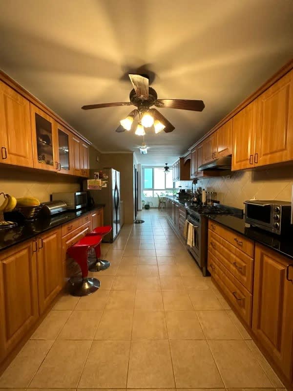 Galley kitchen with wood cabinets, granite counters, stainless appliances in PH Sol Marina Panama