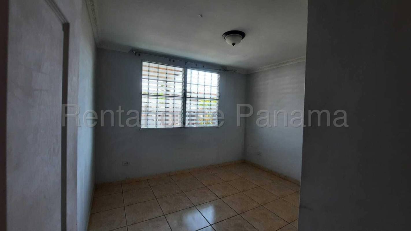 Bedroom featuring built-in closet, tiled floor and window with security bars in Brisas del Golf home Panama
