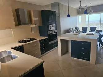 Contemporary kitchen with granite island seating, appliances and dining area in oceanview condo at PH Vista Mar