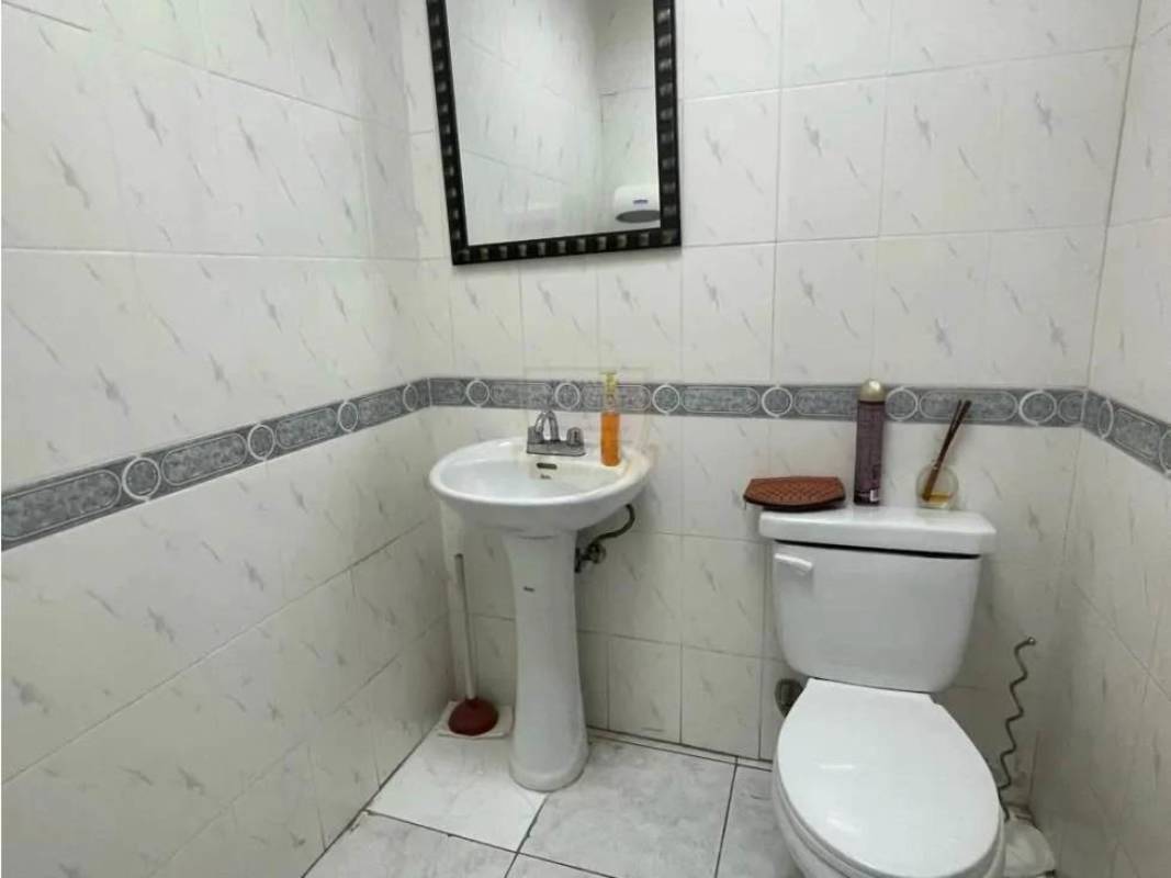Ceramic tiled bathroom with pedestal sink and mirror in commercial office Panama