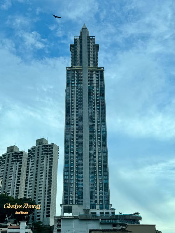 Modern skyscraper with pointed rooftop surrounded by city landscape at Pacific Hills Panama City