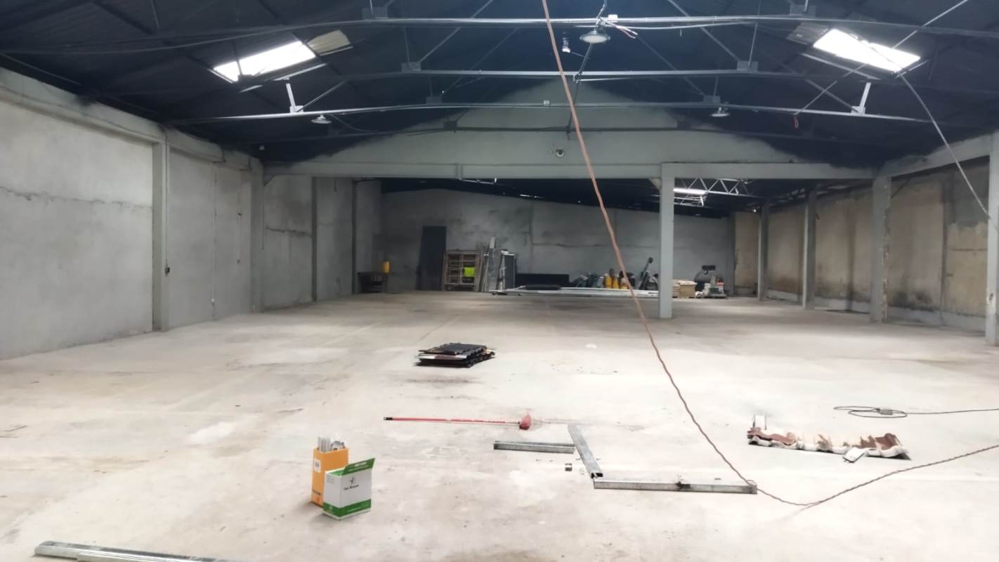 Warehouse open space with unfinished concrete floor and exposed ceiling beams in La Loceria Panama