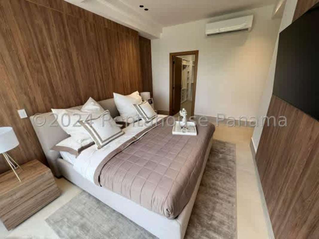 Modern master bedroom with wood wall and large window overlooking Santa Maria golf in duplex apartment PH Ocean House Panama