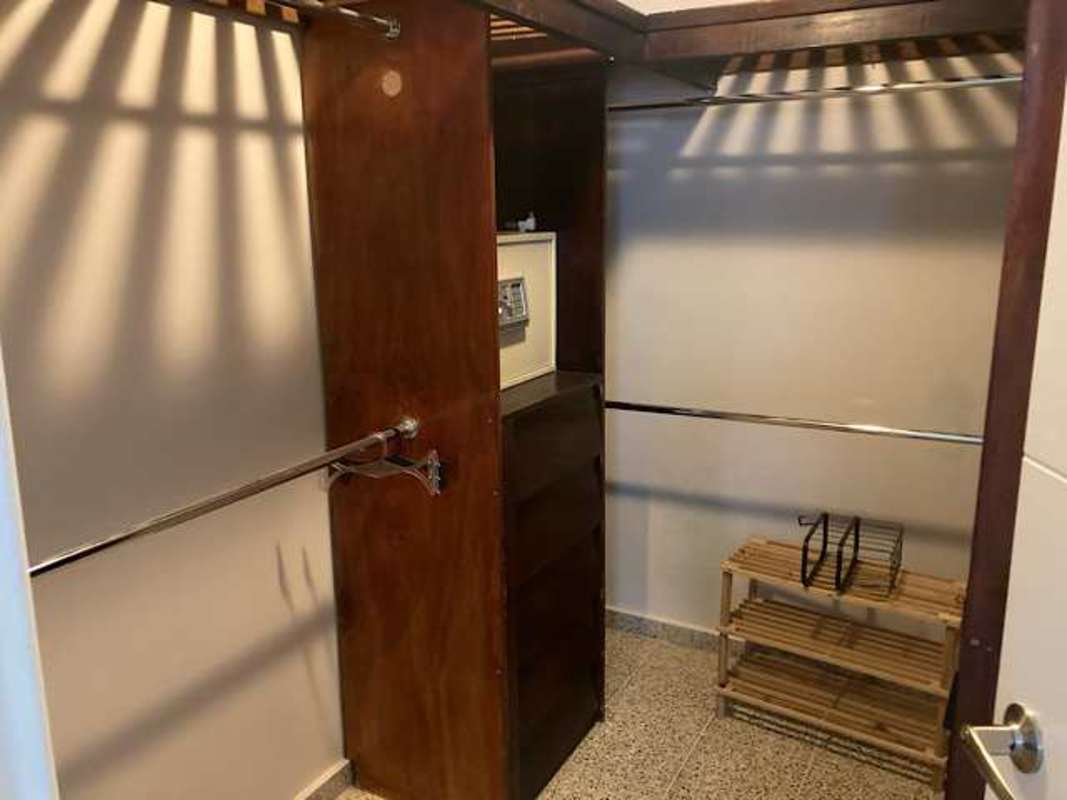 Spacious walk-in closet with wood shelves hanging rods built-in safe walk-in storage Panama rental home
