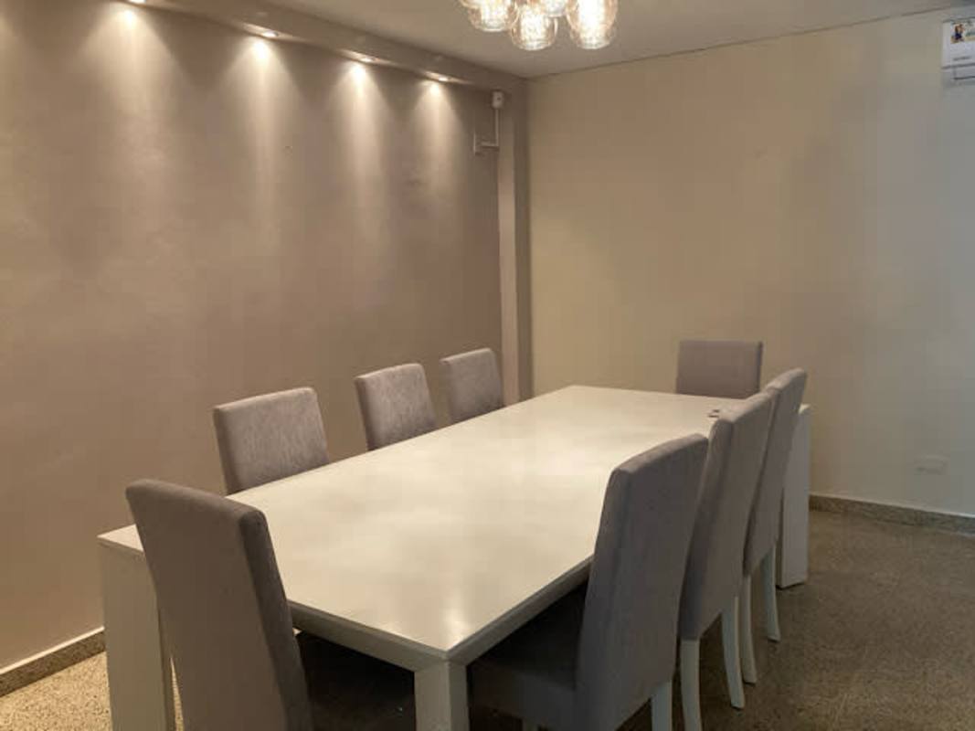 Elegant dining area with rectangular table 8 gray chairs recessed lights and chandelier Panama rental home