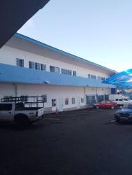 Exterior two-story commercial plaza with blue roof ample parking and glass windows, Arraiján Panama