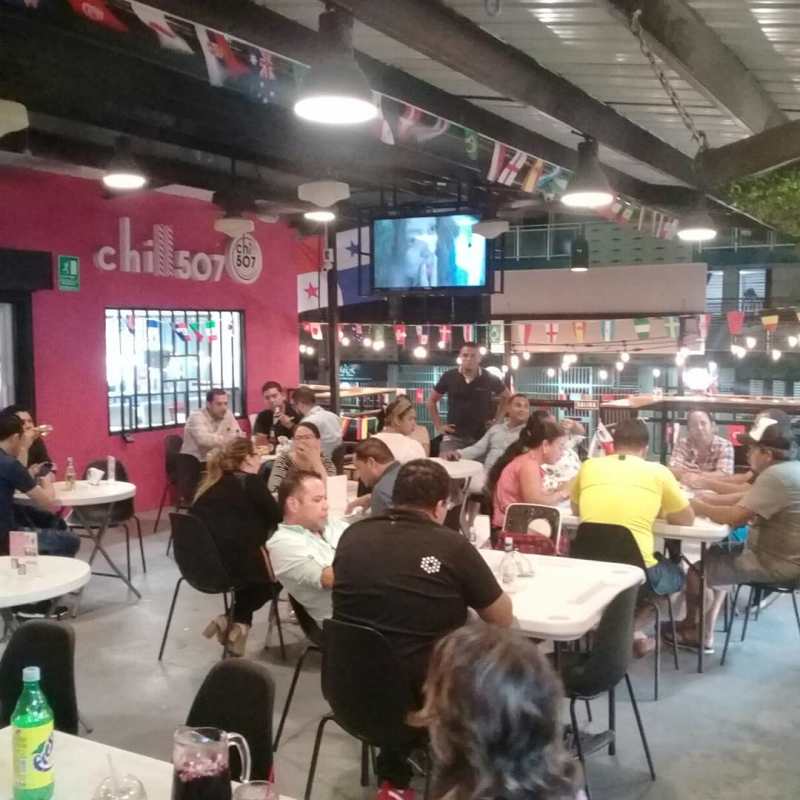 Restaurant interior with flags, string lights and seating inside Food Bazaar El Cangrejo