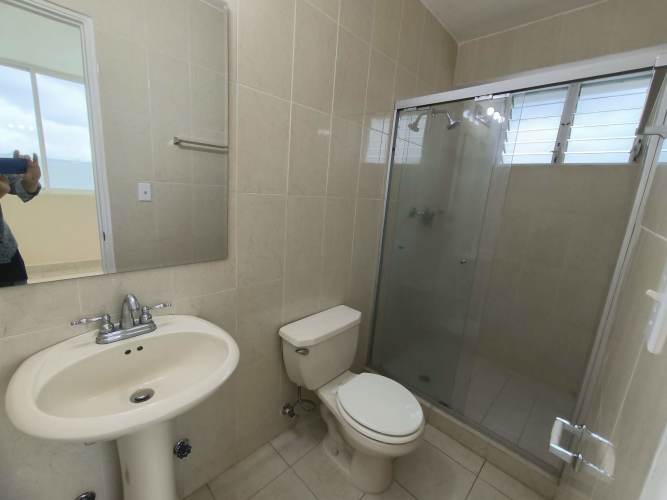Modern bathroom with beige tile and glass enclosed shower at PH Edison Park Panama