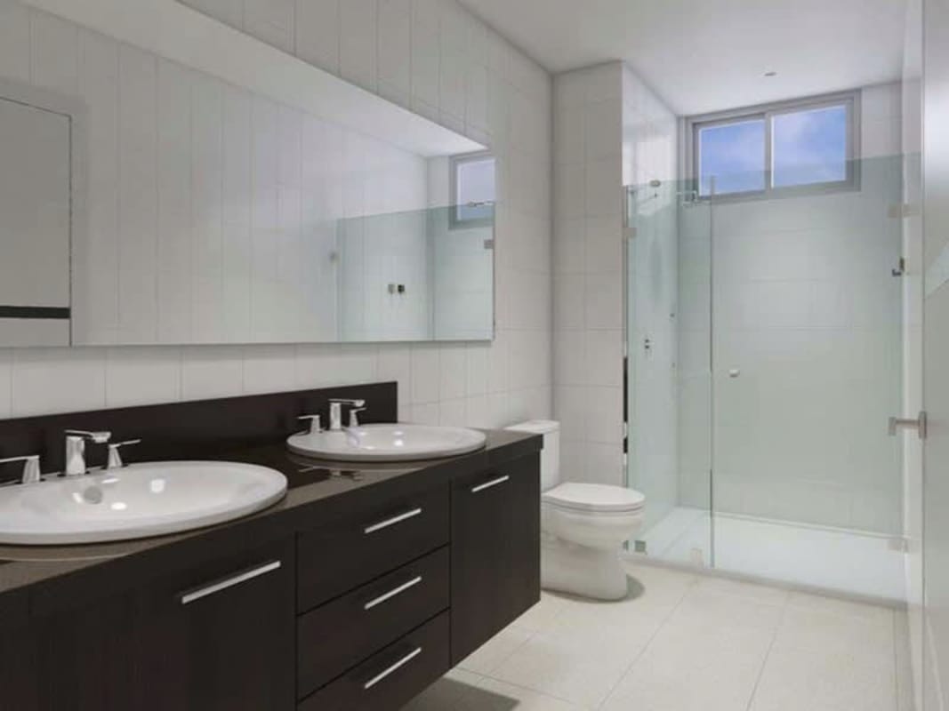 Contemporary bathroom with double sinks, large mirror, glass enclosed shower, tile walls at Forest Gate in Albrook Panama