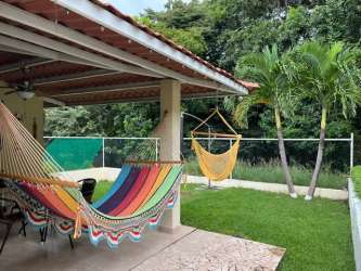 Single-story house front porch with hammock lush garden tropical Las Lajas Panama