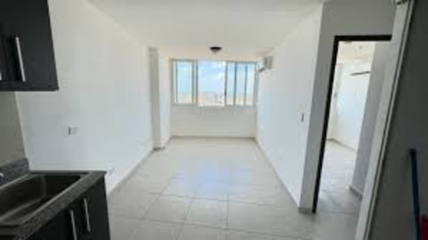 Minimalist living area with open kitchen, tiled floors, large window and balcony ocean views in Bay View Tower Panama City