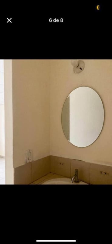 Minimalist bathroom with oval mirror and beige tile in Don Bosco apartment Panama