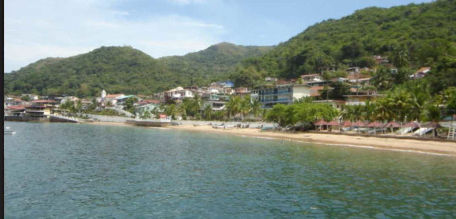 Beachfront village with hillside homes lush greenery calm ocean waters Isla Taboga Panama