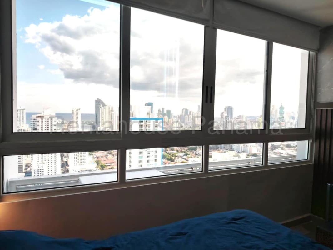 Master bedroom with large windows and sweeping city and ocean views at PH Quadrat San Francisco Panama City