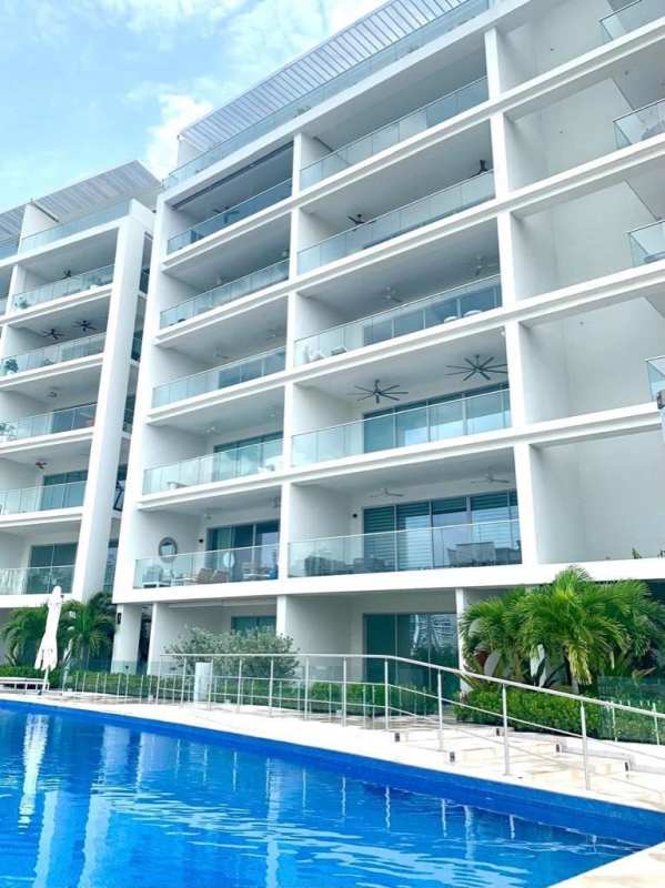 Luxury Ocean Reef Island condo tower with glass balconies, infinity pool, palm landscaping