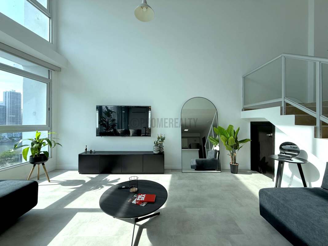 Open living and dining area with double-height glass walls facing ocean and skyline in PH BICSA Tower Panama