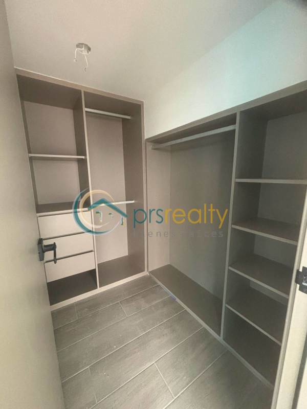 Modern walk-in closet with built-in shelves and drawers in luxury apartment PH Dovle