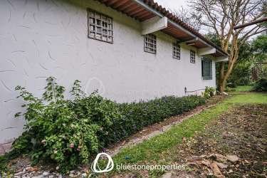 Rustic kitchen with wood cabinets, natural light, breakfast bar, and garden view in estate house El Valle Panama