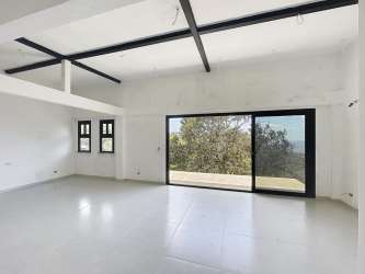 Living room with floor-to-ceiling glass and valley views modern mountain house Panama