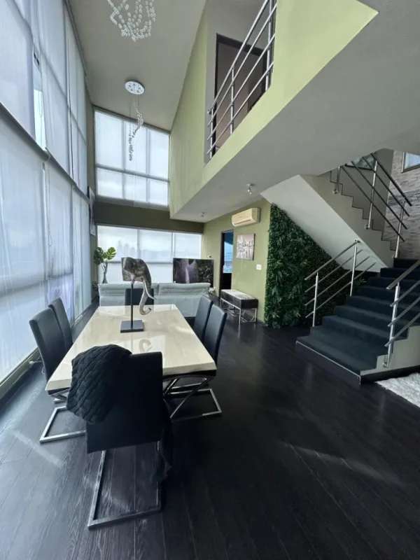 Double height living room with floor-to-ceiling windows and balcony at PH Park Loft Panama City