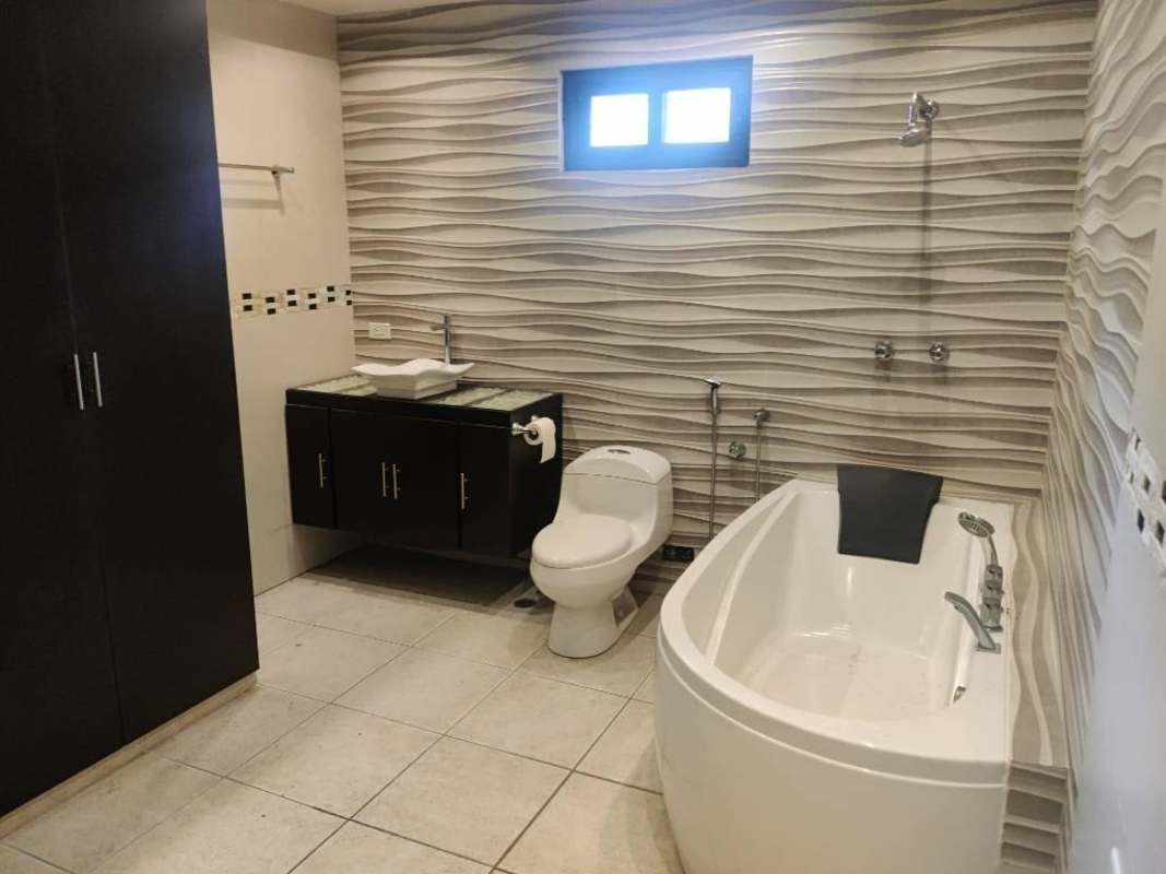 Contemporary bathroom with wave-pattern wall tiles, bathtub, vanity sink and toilet Villa de las Fuentes Panama