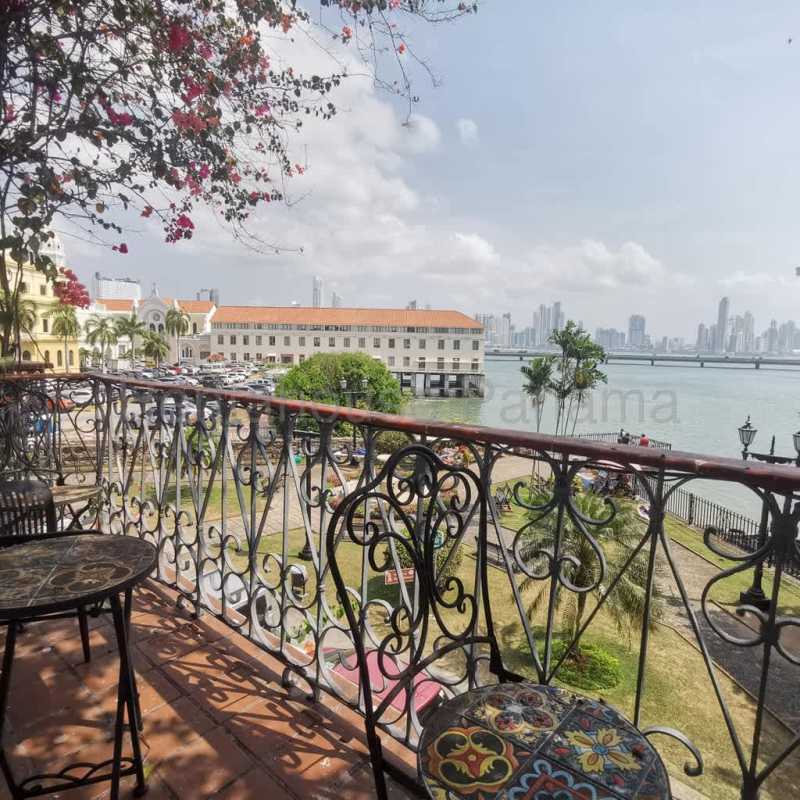 Living room with terracotta floors, large windows, balcony access in historic apartment Casco Viejo Panama City